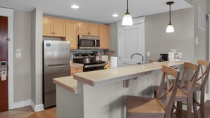 A modern kitchen with wooden cabinets, stainless steel appliances, and a central island with bar stools.