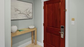 A hallway with a wooden console table, a white vase, and a framed artwork on the wall.
