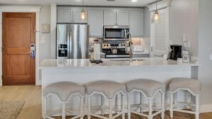 A modern kitchen with a central island, stainless steel appliances, and bar stools.