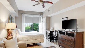 A hotel room with a bed, a desk, a television, and a ceiling fan.