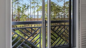 Une pièce dotée d’une porte-fenêtre coulissante donnant sur un balcon avec un plancher en bois et une balustrade à treillis.