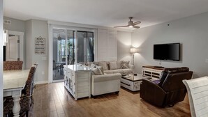 Un salon moderne comprenant un canapé, un fauteuil inclinable, un téléviseur et un coin repas avec une table et des chaises.
