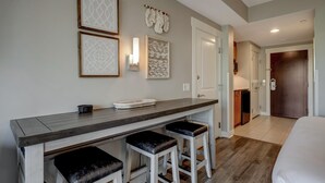 A modern hotel room with a kitchenette, a bar area with stools, and a bed. - 3rd-Floor Bayfront Serenity: 2 Bedroom, 3 Baths, Sunset Views, Private Balcony at Sandestin Golf and Beach Resort! (Miramar Beach)