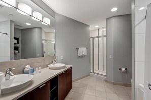 A modern bathroom with two sinks, a large mirror, and a glass shower enclosure.