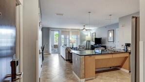 A modern kitchen with a central island, a dining area with a sofa, and a TV.