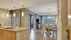 Una cocina moderna con una isla central, armarios de madera y un comedor con candelabro.