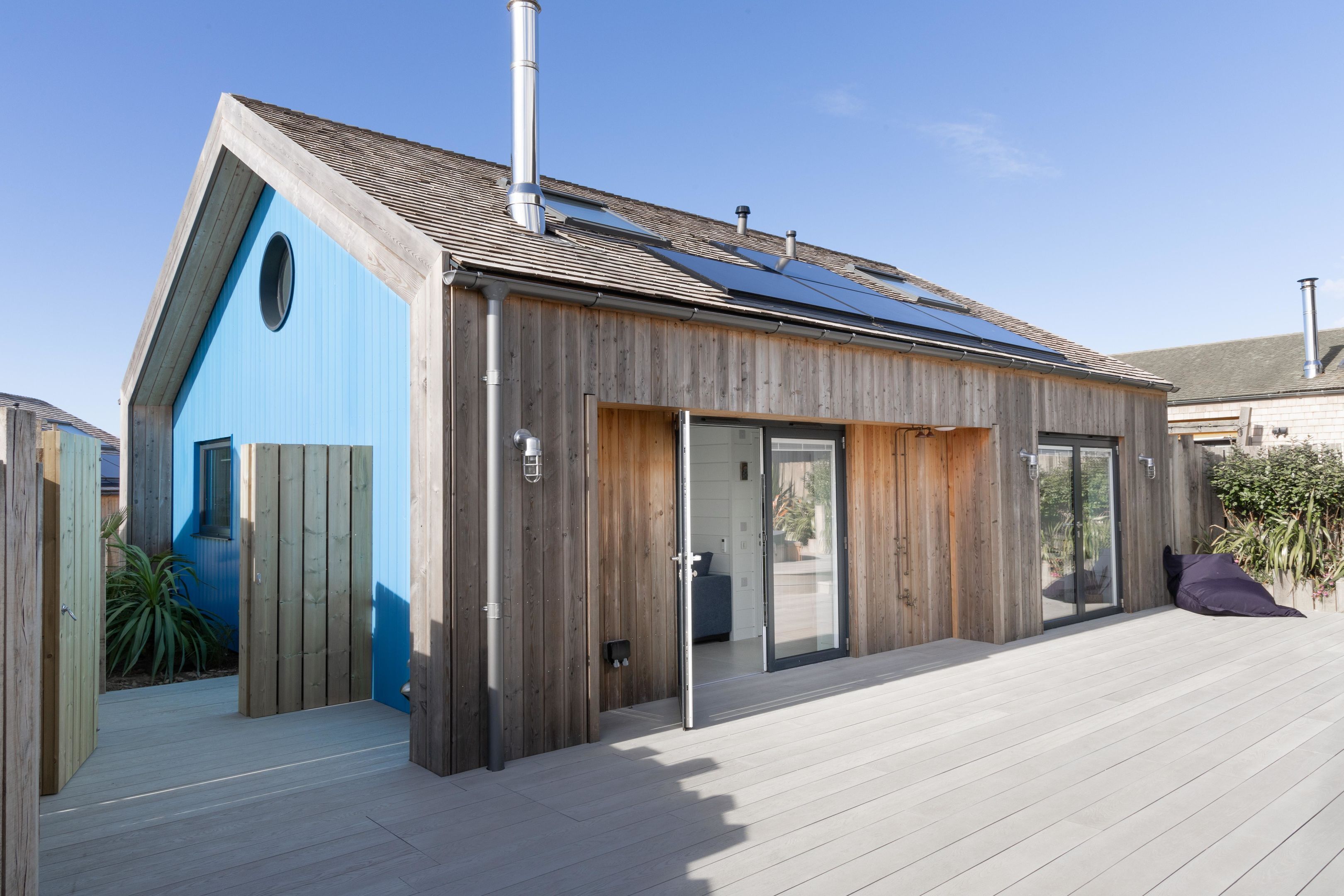 Una casa moderna con techo inclinado, paneles solares y fachada de madera.