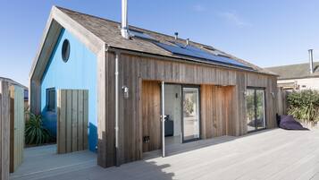 Una casa moderna con techo inclinado, paneles solares y fachada de madera.