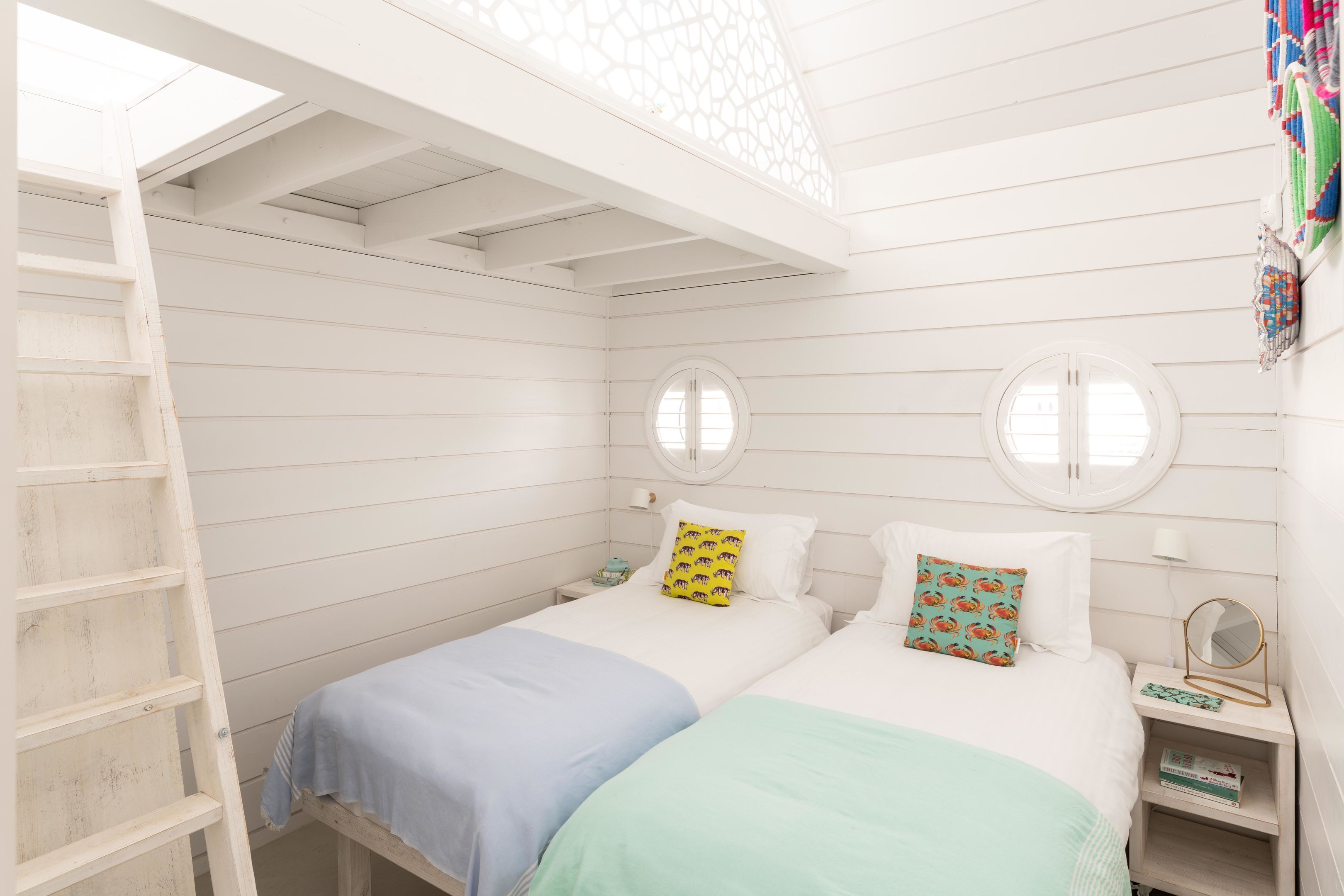 A room with two beds, a ladder, and a skylight.
