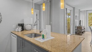 Eine moderne Küche mit Granit Arbeitsplatten, Edelstahlgeräten und Pendelleuchten.