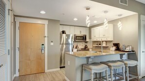 A modern kitchen with white cabinets, stainless steel appliances, and a central island with bar stools.