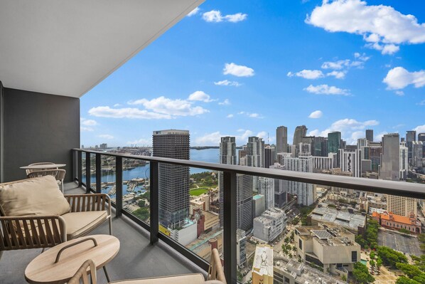 A balcony with a city view, including high-rise buildings and a body of water.