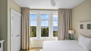 A bedroom with a bed, a nightstand, a lamp, a ceiling fan, and a window with curtains.