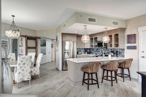 Una cocina moderna con una isla central, taburetes de bar e iluminación colgante.