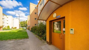 Un edificio con fachada amarilla, una puerta con teclado numérico y un cartel sobre la puerta.