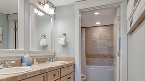 A bathroom with two sinks, a bathtub, and a shower.