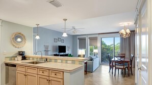 A modern kitchen with a central island, a dining area with a table and chairs, and a view of the outdoors.