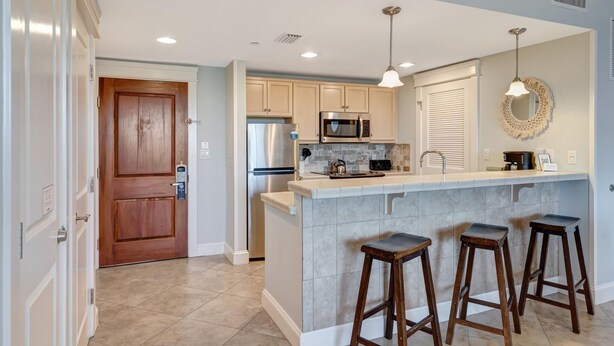 A modern kitchen with a central island, stainless steel appliances, and wooden stools.