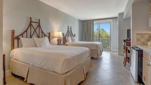 A hotel room with two beds, a balcony, and a kitchenette.