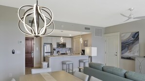 A modern kitchen with a central island, a dining area with a table and chairs, and a living area with a sofa.