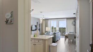 A modern hotel room with a kitchenette, a balcony with a view, and a dining area.