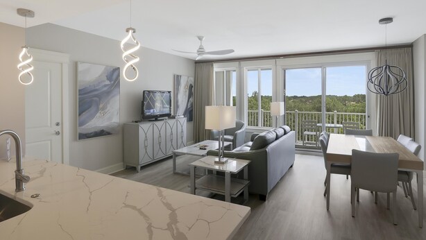 A modern living room with a sofa, dining table, and kitchen area.