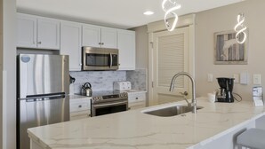 A modern kitchen with stainless steel appliances, a marble countertop, and a sink.