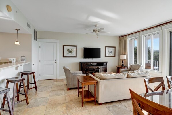A spacious living room with a sofa, a TV, and a dining area with a table and chairs.