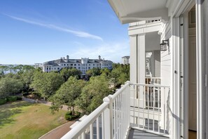 A balcony with a view of a large, multi-story building surrounded by trees.