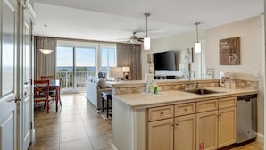 A modern kitchen with a large island, a dining area with a view, and a living space with a balcony. - Stunning Bay Views on the 6th Floor:  Two bedroom with Fully Equipped Kitchen, Sleeper Sofa at Sandestin Golf and Beach Resort! (Miramar Beach)