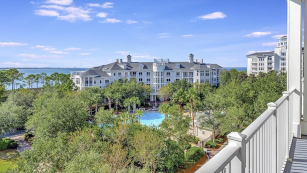 A large hotel with a swimming pool surrounded by lush greenery and a view of the ocean. - Stunning Bay Views on the 6th Floor:  Two bedroom with Fully Equipped Kitchen, Sleeper Sofa at Sandestin Golf and Beach Resort! (Miramar Beach)
