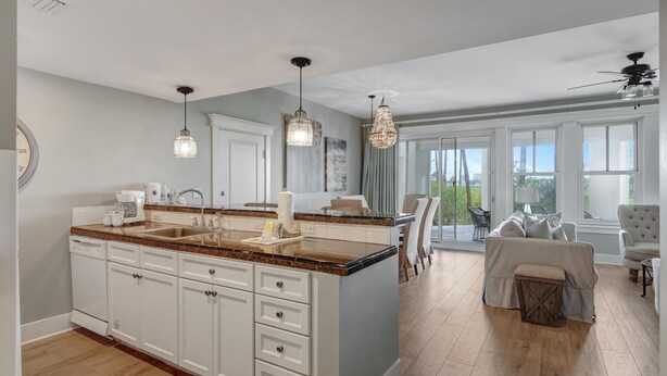 A spacious kitchen with a large island, white cabinetry, and pendant lighting.