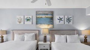 A hotel room with two beds, a nightstand with a lamp, and artwork on the wall.
