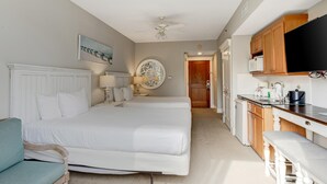 Habitación de hotel con dos camas, kitchenette y zona de comedor.