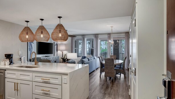 A modern kitchen with a central island, pendant lights, and a dining area with a round table and chairs.