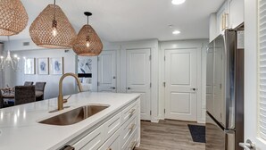 A modern kitchen with white cabinetry, a stainless steel sink, and pendant lights.