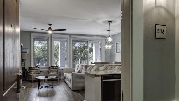 Amplia sala de estar con ventilador de techo, isla de cocina y mesa de comedor.