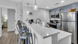 A modern kitchen with a central island, stainless steel appliances, and pendant lighting.