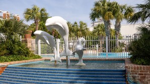 A pool area with steps leading into the water, surrounded by a white fence and palm trees.