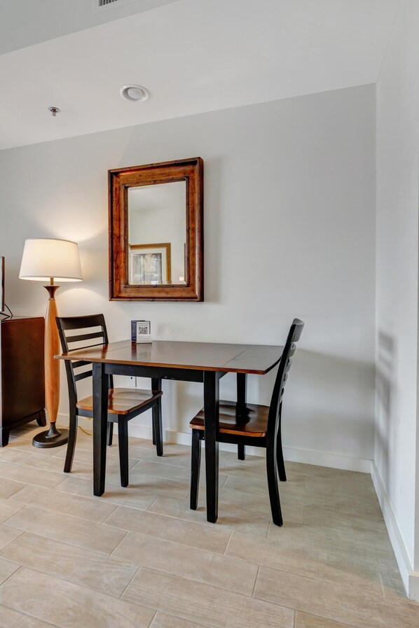 A dining area with a wooden table, four chairs, a lamp, and a mirror on the wall.