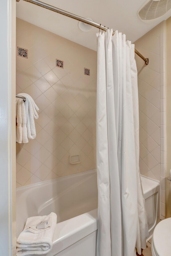 Un baño con bañera, cortina de ducha y un perchero con toallas.