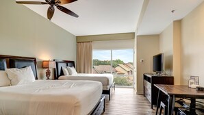A hotel room with two beds, a desk, a television, and a balcony with a view of houses. - Relaxing Oasis in Luau: Serene Two-Bedroom Retreat with 3 Beds and Scenic Views at Sandestin Golf and Beach Resort! (Miramar Beach)