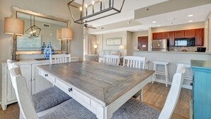 Una cocina moderna con una isla central, muebles blancos y un espejo grande sobre la encimera.
