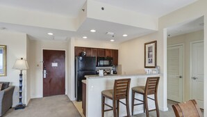 A compact kitchen with a central island, wooden cabinets, and a refrigerator.