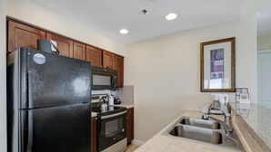 A modern kitchen with a black refrigerator, stainless steel sink, and wooden cabinets.