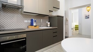 Una cocina moderna con horno empotrado, cafetera y lavabo.