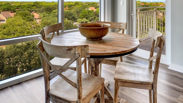 A dining area with a round table, wooden chairs, and a hanging light fixture.