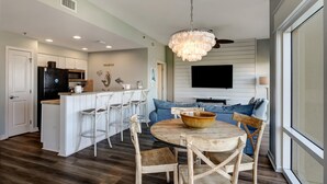 A modern kitchen with white cabinetry, a central island with bar stools, and a dining table with chairs.
