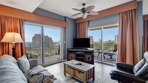 A modern living room with a sofa, a coffee table, a TV, and a ceiling fan.