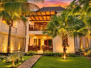 A two-story building with a covered patio, palm trees, and a stone pathway leading to the entrance. - 5-Acre Private Jungle Estate | Ocean Views, Huge Pool, Chef & Transportation (Playa Tamarindo)